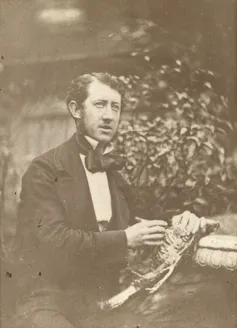 Black and white portrait of man sat down in formal dress.