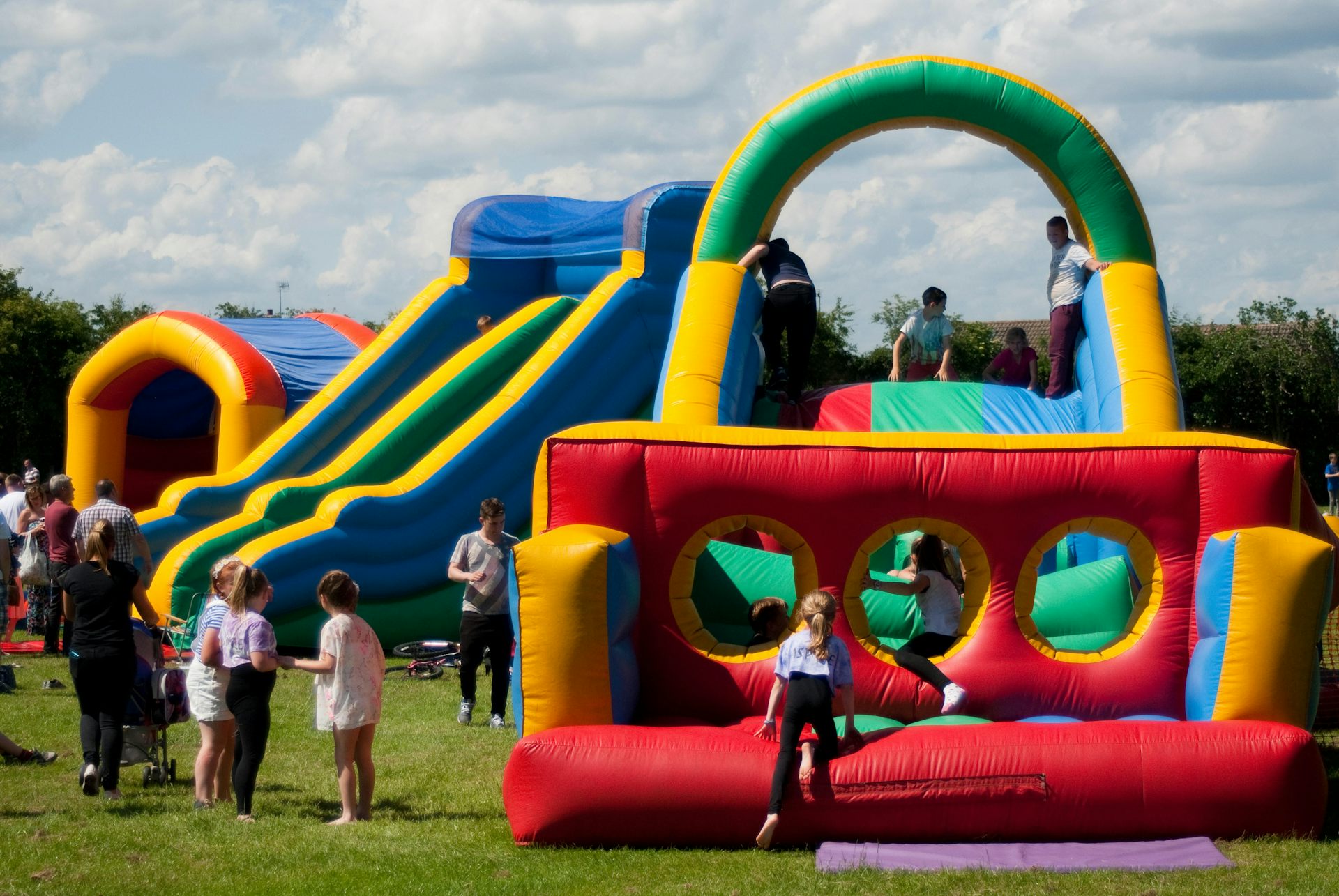 Several bouncy castles in a field with children and adults.