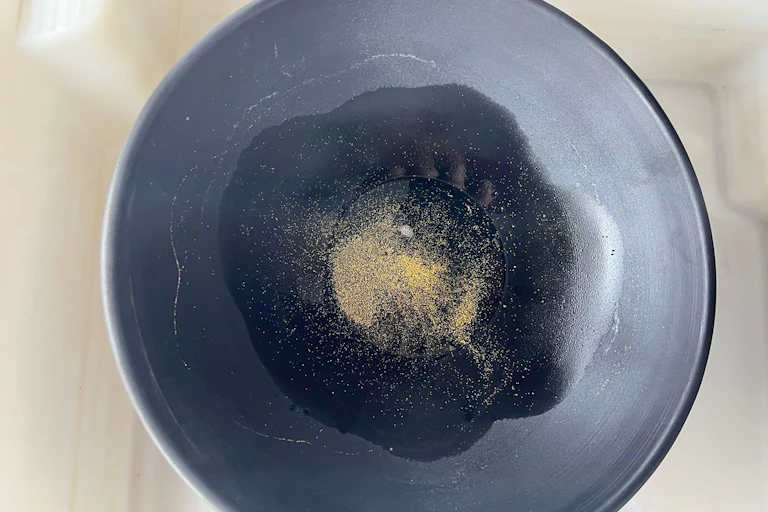 Numa bateia, um fino pó dourado, que é o ouro, foi separado dos sedimentos