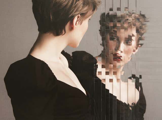 A woman looks at a distorted mirror image of herself.