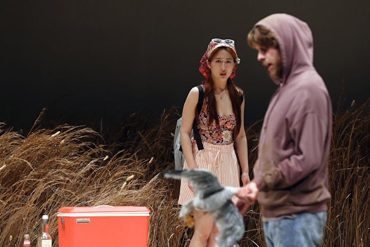 A woman looks at a man holding a seagull.