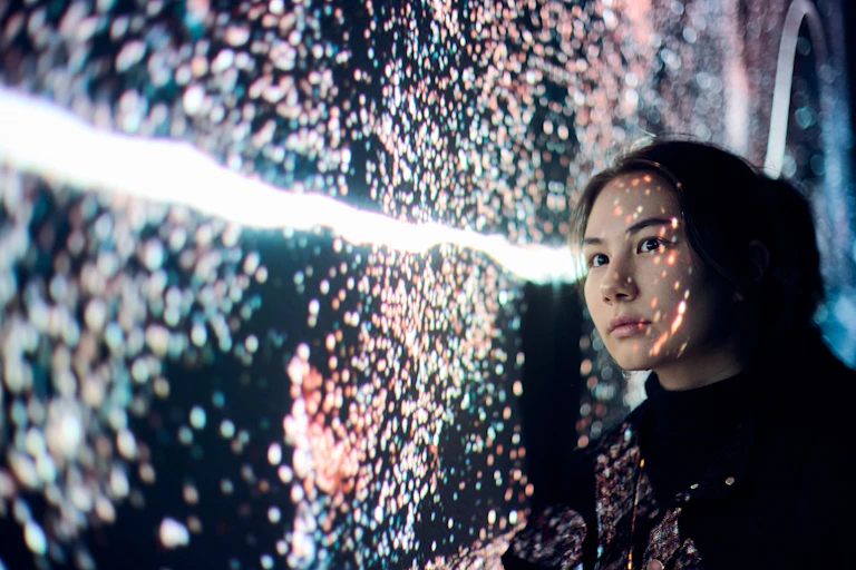 A woman stares at dots of light.