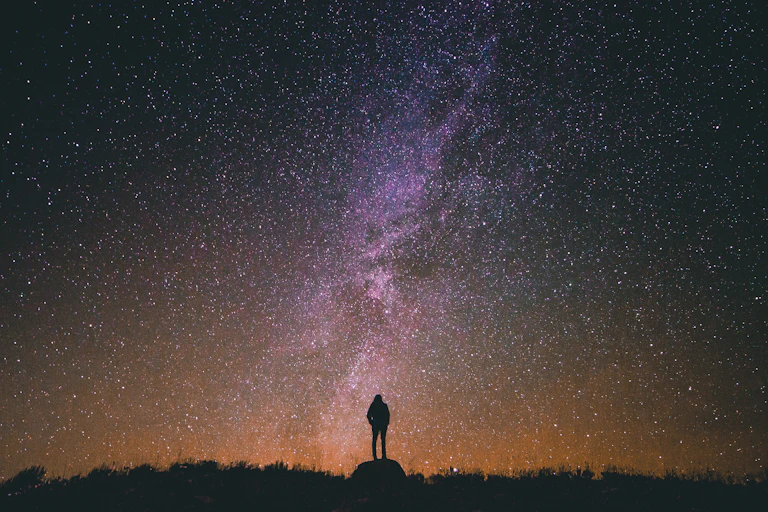 Photo of a person silhouetted against a starry sky.