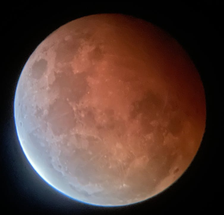 Powiększony widok Księżyca z jedną stroną w odcieniu czerwieni