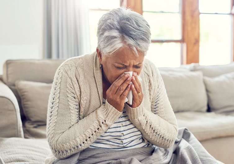 A senior woman blowing her nose.