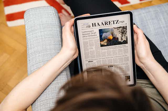 A person reads the Israeli newspaper Haaretz on a tablet.