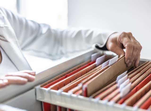 A woman looking through a paper filing system.