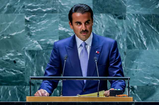 Emir of Qatar, Sheikh Tamim bin Hamad Al Thani delivers a speech standing at a lecturn.