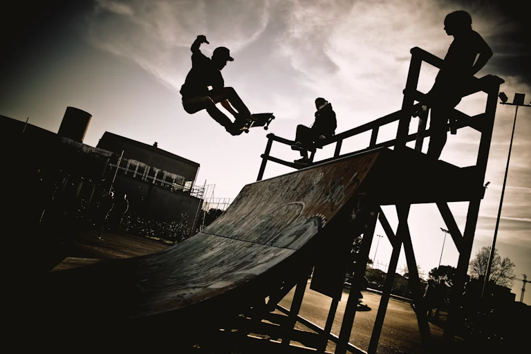 Three skateboarders silhouetted against the sky in black and white.