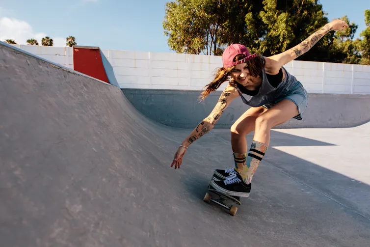 A young woman on a skateboard in a skatepark.