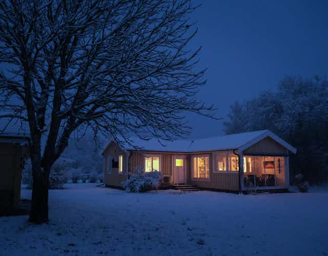 house with glowing windows in a dark snowy landscape