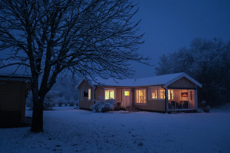 house with glowing windows in a dark snowy landscape