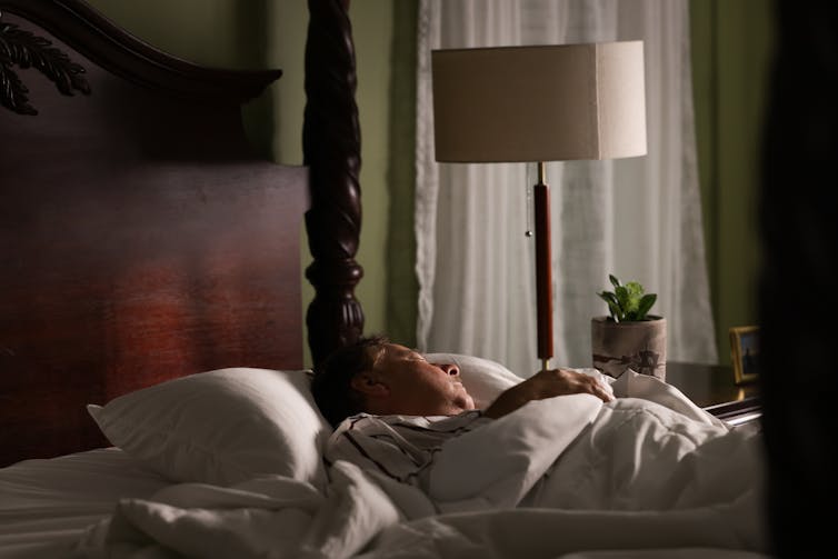 man lying in bed in a room with dim daylight