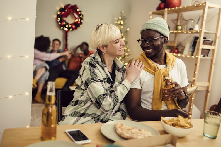 woman with hand on man's shoulder at a holiday gathering