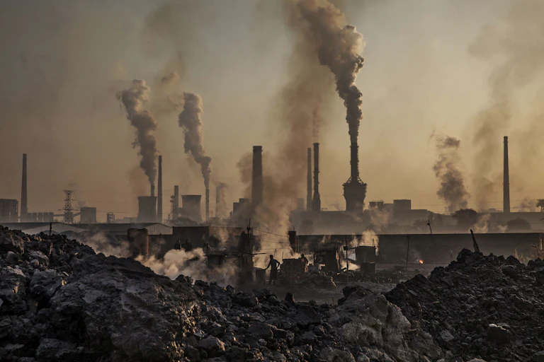 Smoke billows from a large steel plant as a Chinese laborer works at a steel factory.