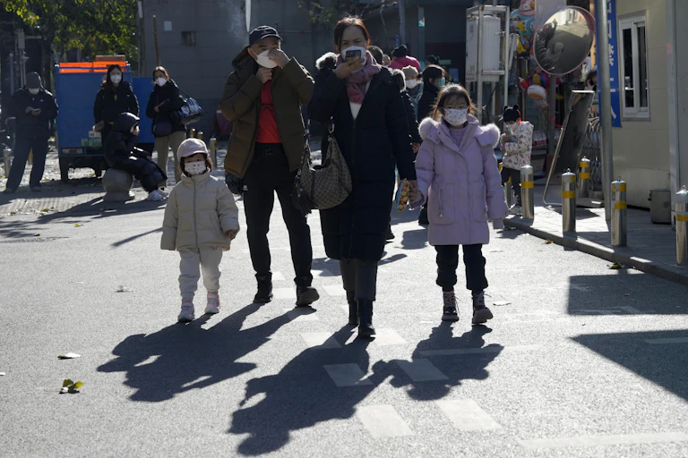 Dos adultos y dos niños caminan por Pekín con máscaras.