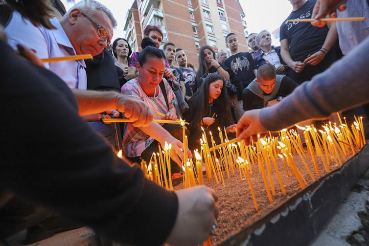 A group of men and women hold candles.