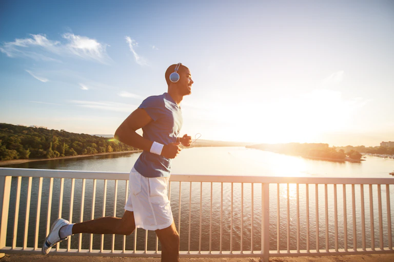 Un homme est en train de faire du jogging sur un pont avec un casque audio sur la tête.