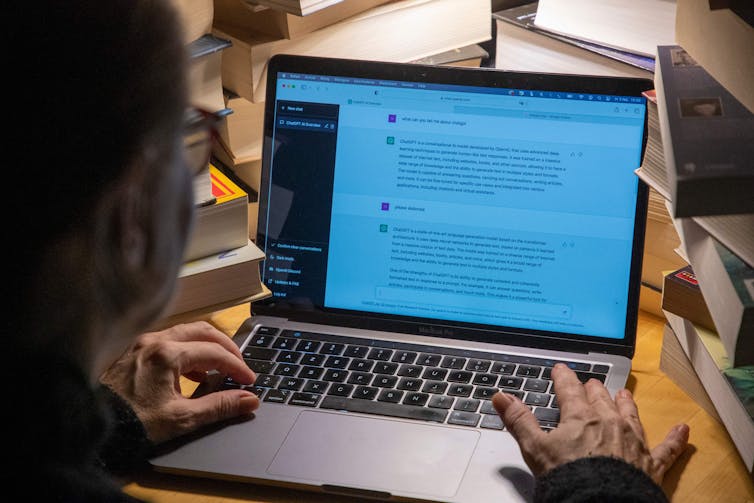 A man wearing glasses looks at a laptop screen, his hands poised over the keyboard, text on the screen