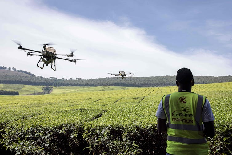 A man flies drones to spread fertilizer on a field in Kenya.