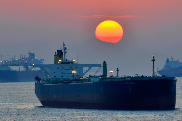 Container vessels under a red setting sun.