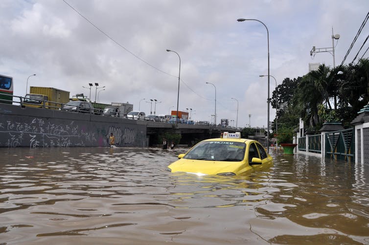 A yellow taxi partially submerged in flood water.