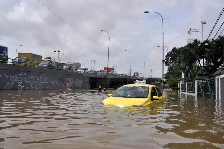 A yellow taxi partially submerged in flood water.