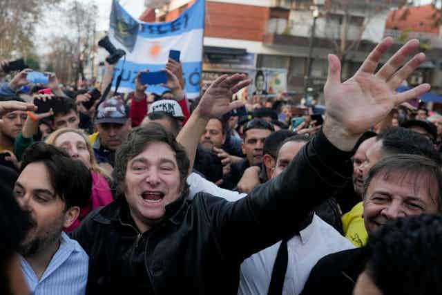 New Argentinian president Javier Melei in a crowd with his arm in the air.