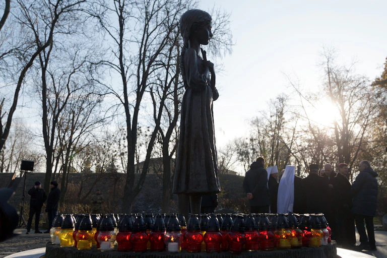 The statue of a girl with lit lanterns at her feet.