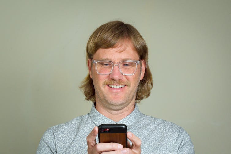 man smiling looking at mobile phone