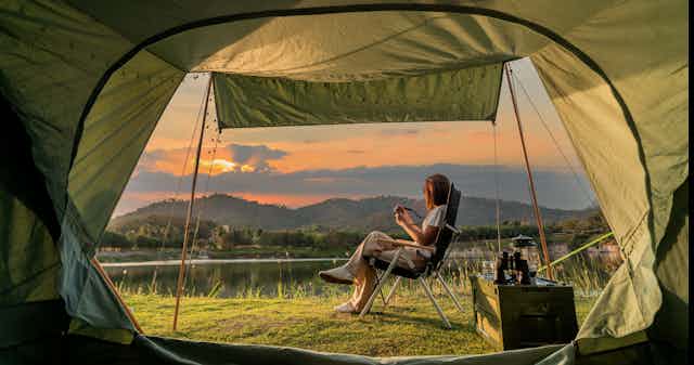 Woman sits outside her tent