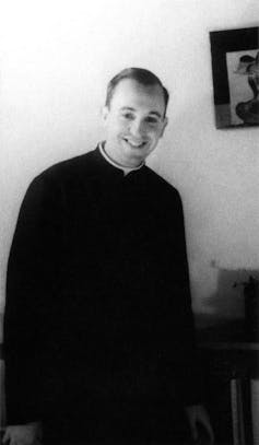 A smiling young man, dressed in black, poses for a photo.