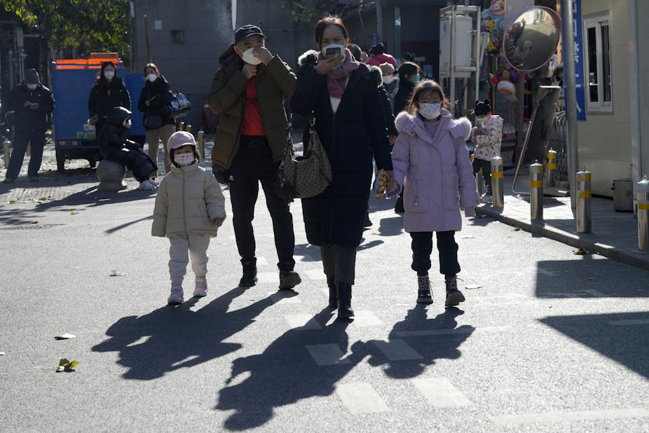 Two adults and two children walking in Beijing wearing masks.