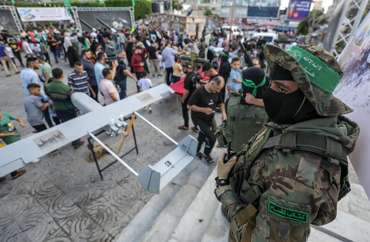 Hamas fighters in battle gear oversee an array of military equipment, Gaza, July 2023.