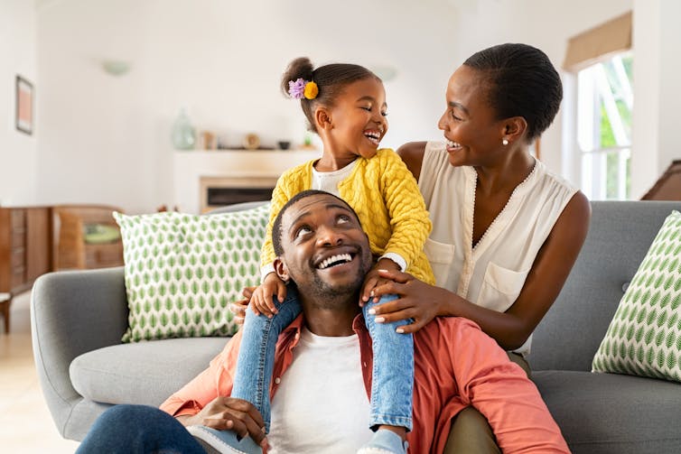 A photo of a smiling mother, father and daughter.