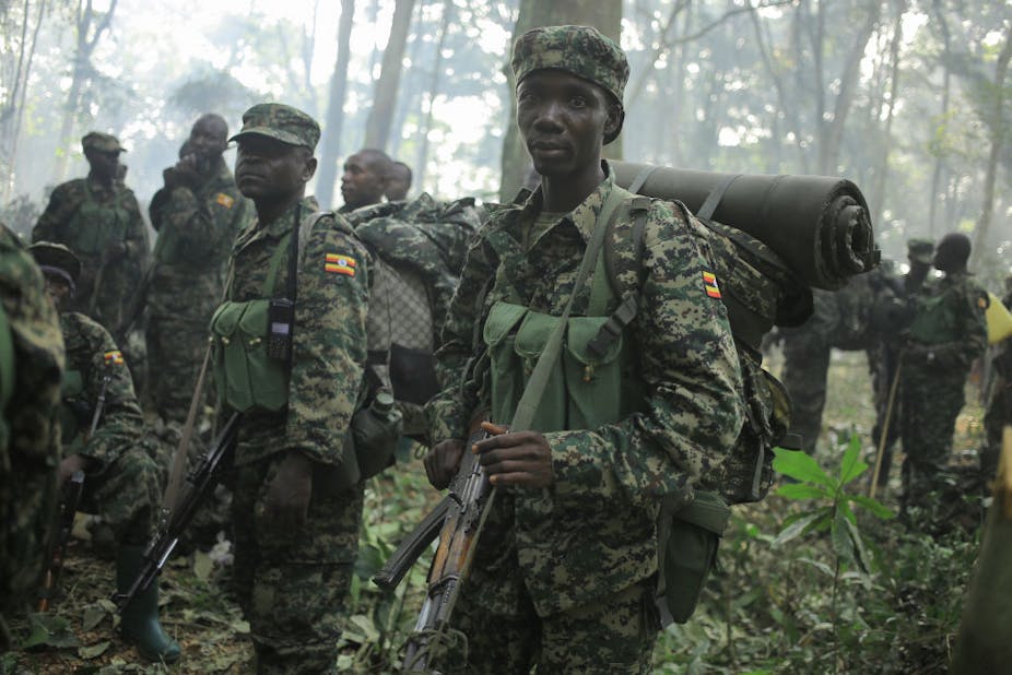 Soldiers stand in a forest holding guns