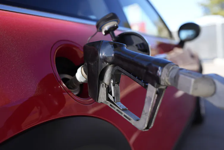 A fuel pump seen filling a red car.