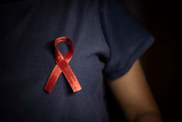 Close-up of red ribbon pinned to the chest of a person wearing a black T-shirt