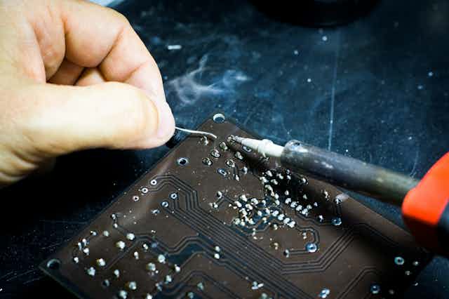 close up of a hand repairing a circuit board