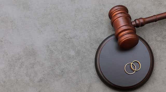 A gavel seen next to two wedding rings.