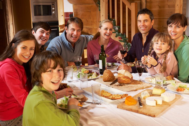 Two families seen sitting around a holiday table.