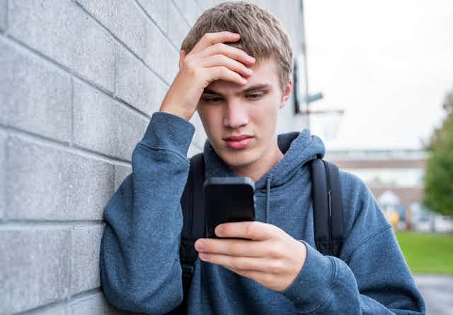 A teen boy viewing something upsetting on his phone