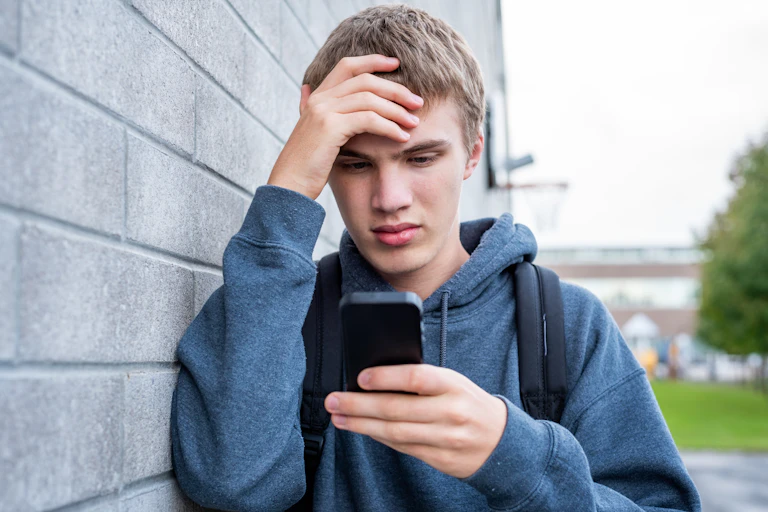 A teen boy viewing something upsetting on his phone