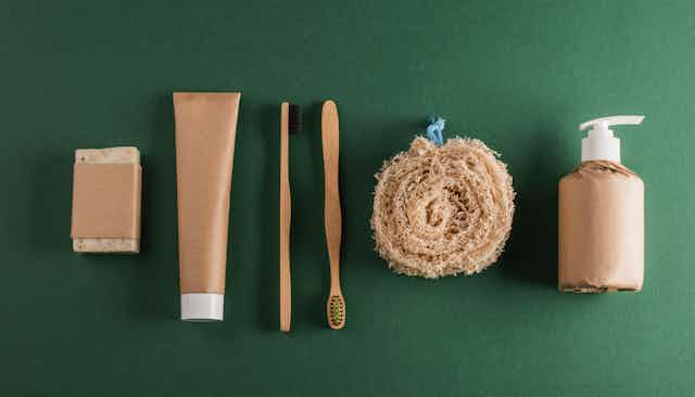 A green background with wooden toothbrushes and paper wrapped products
