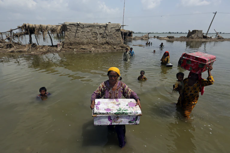 Women carry belongings salvaged from their flooded home after monsoon rains, in the Qambar Shahdadkot district of Sindh Province, of Pakistan, Sept. 6, 2022