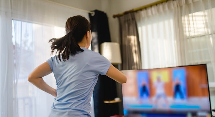 A woman does exercise in front of the TV.