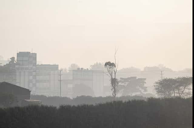 View of indistinct city skyline through greyish haze.