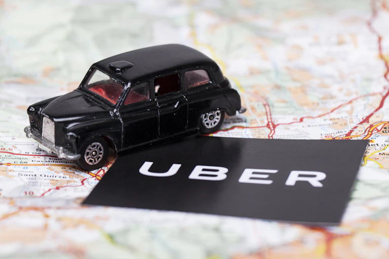 black cab on a man next to an Uber sign