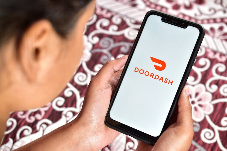Woman holding a phone that says DoorDash