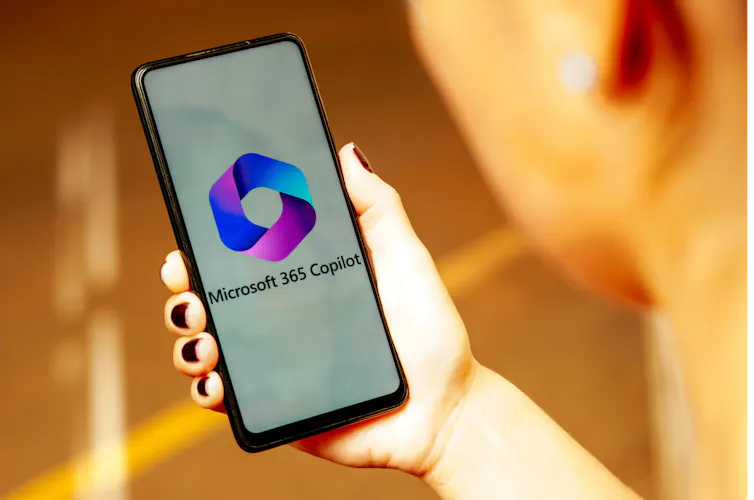 The Microsoft 365 Copilot logo is displayed on a smartphone screen held in a hand.